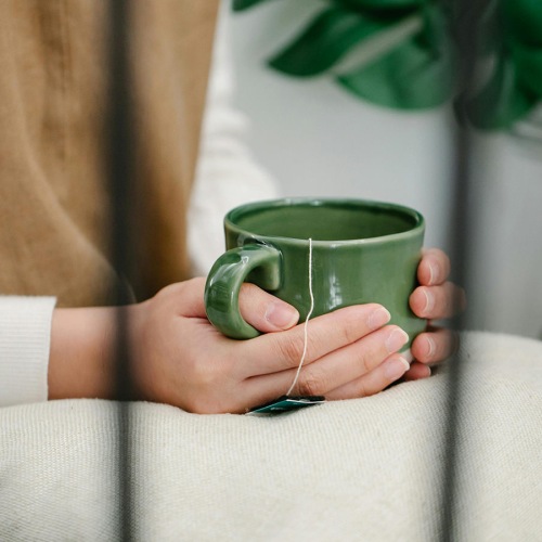 woman holds a cup of tea on a pillow